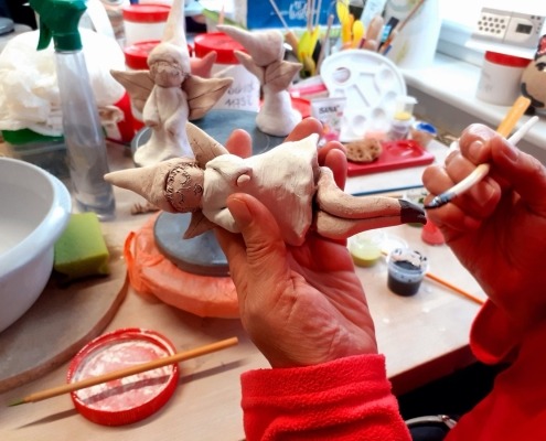 Eine Person bemalt eine kleine Keramikfigur.