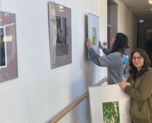 Zwei Personen tauschen Bildern an einer Wand aus.