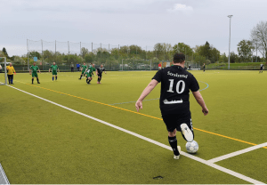 Ein Spieler der Fußballmannschaft der Stralsunder Werkstätten steht an der Ecke des Fußballfeldes und schießt den Ball.