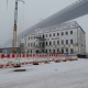 Die neue Betriebsstätte der Stralsunder Werkstätten mitten im Baugeschehen befindet sich im dichten Nebel. Im Vordergrund sind Bauzäune, ein Kran sowie ein Baugerüst zu sehen.