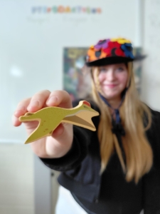 Eine Person zeigt die Figur eines Dinosauriers in die Kamera.
