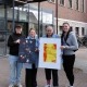 Vier Personen stehen vor dem Helios Hanseklinikum in Stralsund und halten zwei Bilder der Wanderfotoausstellung der Stralsunder Werkstätten in den Händen.