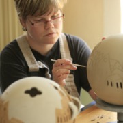 Eine Person bemalt eine Keramikkugel per Hand.