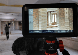 Das Foto zeigt den Blick auf den Bildschirm einer Filmkamera. Auf dem Bildschirm sind unverputzte Wände einer Baustelle zu sehen.