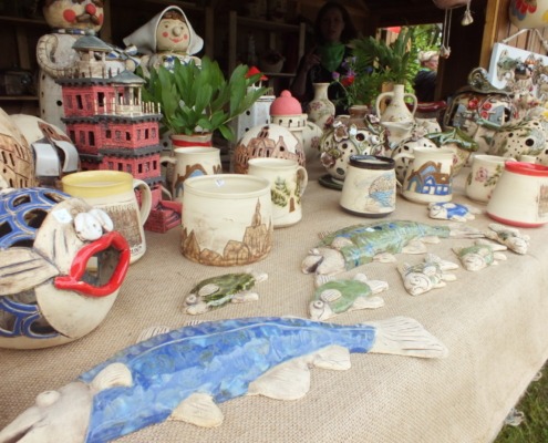 Blick in die Verkaufshütte mit Keramikprodukten, im Vodergrund liegen Keramikfische
