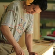 Eine Person mit Gehörschutz arbeitet an einem Holzrahmen.