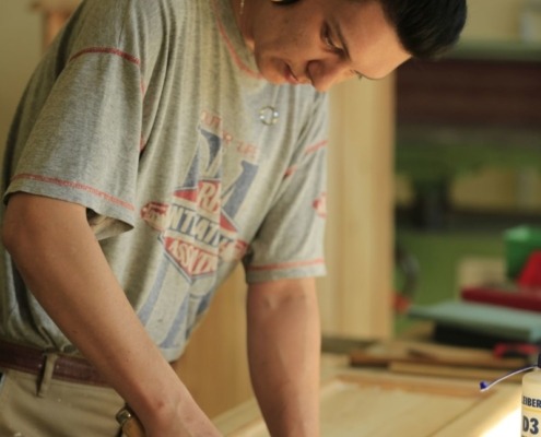 Eine Person mit Gehörschutz arbeitet an einem Holzrahmen.