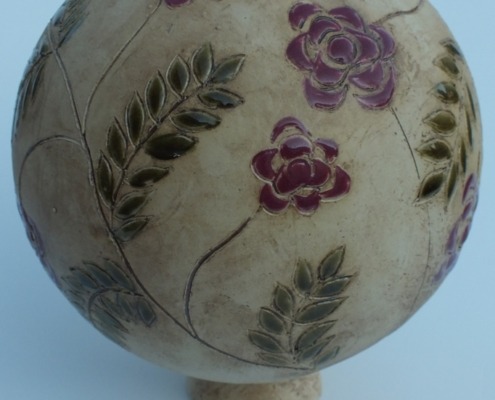eine Keramikkugel mit Blüten und Blättern für den Garten