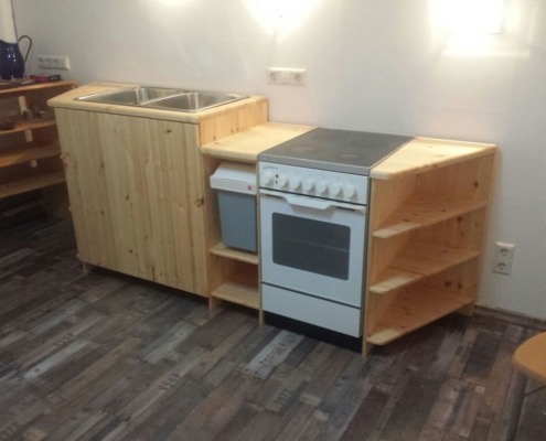 aus Holz gebaute Küche inklusive Waschbecken, Ofen und Kochfeld