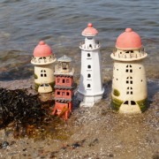 vier Keramikleuchttürme in unterschiedlichen Größen am Strand