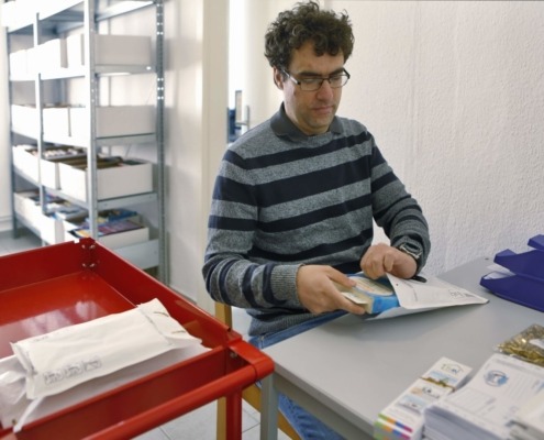 Eine Person verpackt Bücher in Briefumschläge.