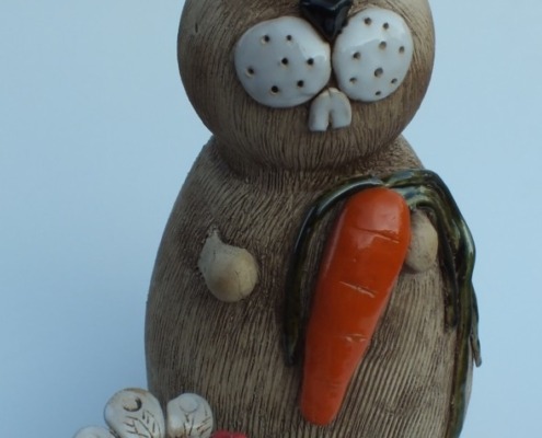 ein Hase aus Keramik mit einer Möhre in der Pfote, davor ein Huhn aus Keramik