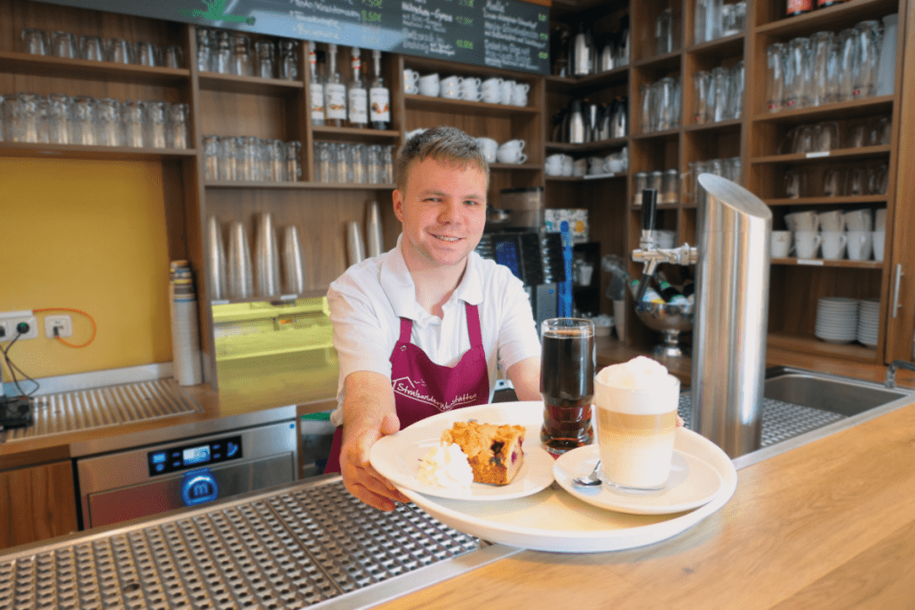 Service_Delikater Eine Person serviert im Bistro ein Kaffeegedeck.