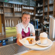 Service_Delikater Eine Person serviert im Bistro ein Kaffeegedeck.