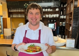 Eine Person serviert im Bistro ein Mittagsgericht.