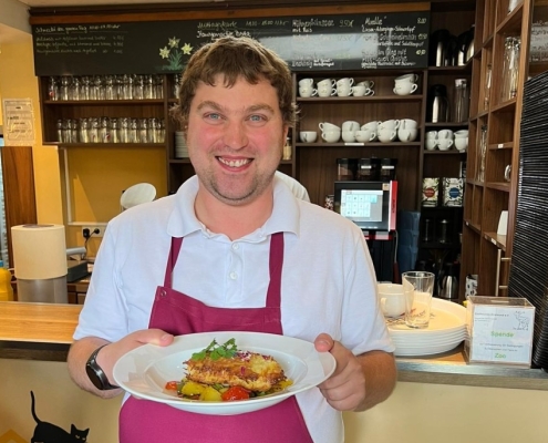 Eine Person serviert im Bistro ein Mittagsgericht.