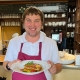 Eine Person serviert im Bistro ein Mittagsgericht.