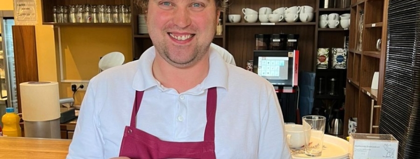 Eine Person serviert im Bistro ein Mittagsgericht.