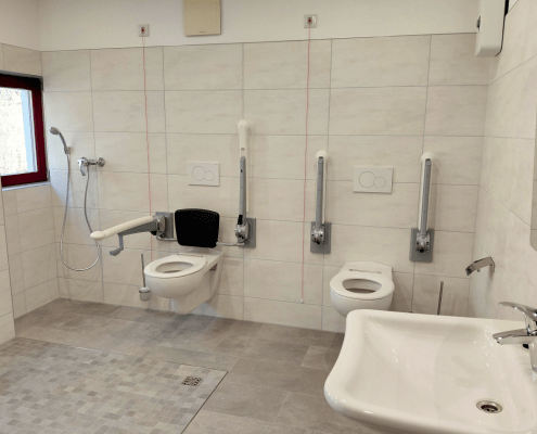 Sanitärraum_Tagesgruppe_Senioren Der Sanitärraum der Tagesgruppe für Senioren verfügt über behindertengerechte WCs, einen Duschbereich und ein Handwaschbecken.