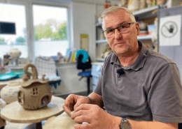 Eine Person formt während des Aktionstages Schichtwechsel in der Keramikwerkstatt der Stralsunder Werkstätten ein Haus aus Ton.