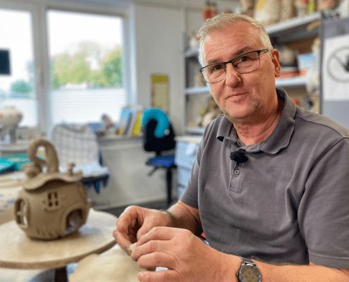 Eine Person formt während des Aktionstages Schichtwechsel in der Keramikwerkstatt der Stralsunder Werkstätten ein Haus aus Ton.