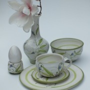 ein weiß-grünes Service, bestehend aus Teller, Unterteller, Tasse, Schale, Eierbecher und Vase