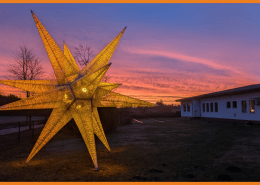Ein 7 Meter hoher Stern vor der Hauptwerkstatt der Stralsunder Werkstätten leuchtet in orange.