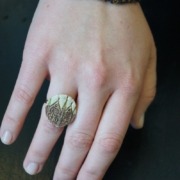 Hand mit einem Ring aus Keramik; der Ring zeigt die Fassade des Stralsunder Rathauses