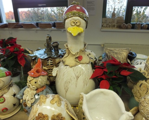 Präsentation von weihnachtlichen Keramikprodukten, in der Mitte steht eine große Gans mit Pudelmütze