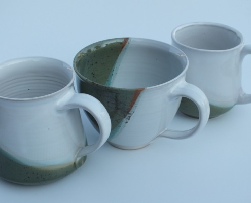 drei Tassen in unterschiedlichen Formen, alle sind teils weiß, teils olivgrün