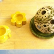 zwei kleine gelbe Teelichthalter in Blumenform und eine grüne Windlichtkugel