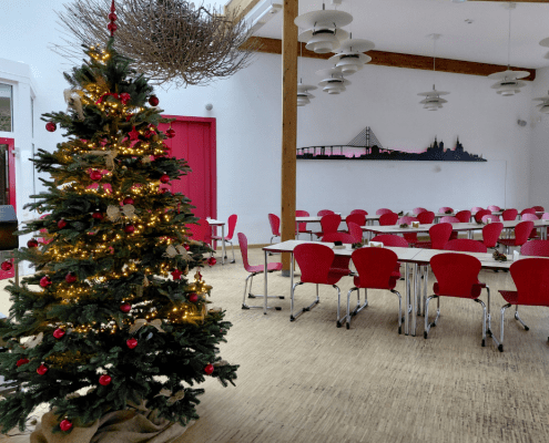 Im Speisesaal der Stralsunder Werkstätten steht ein geschmückter und beleuchteter Weihnachtsbaum.