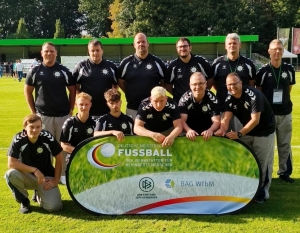 Zwölf Personen, die zur Fußballmannschaft der Stralsunder Werkstätten gehören, stehen auf einem Fußballplatz.