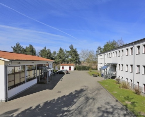 Zwei gegenüberliegende Gebäude mit einer gepflasterten Fläche dazwischen.