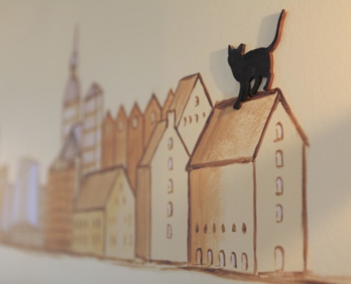 Blick auf eine Wandzeichnung. Zu sehen sind Häuser Stralsunds mit einer Katze auf einem Hausdach.