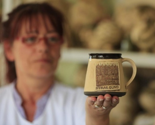 Eine Hand hält eine Tasse mit Stralsundmotiv